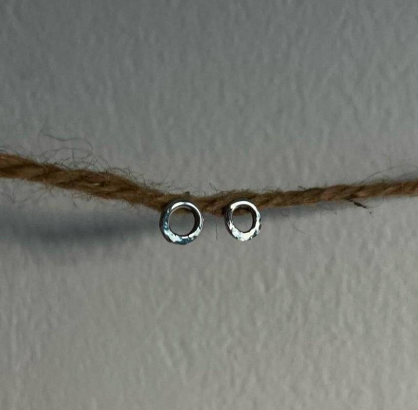 Two silver hoop earrings on a string against a plain background